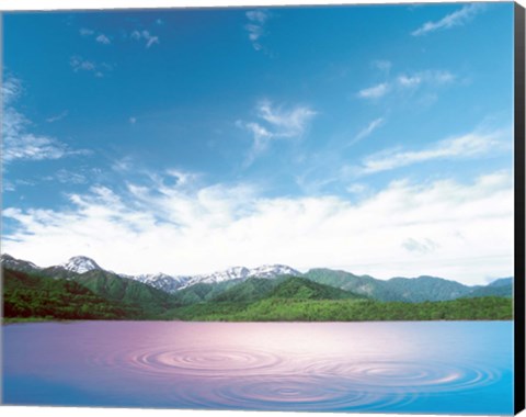 Framed Pink light cast down on two rings in lavender water with deep blue sky and clouds over green mountains in distance Print