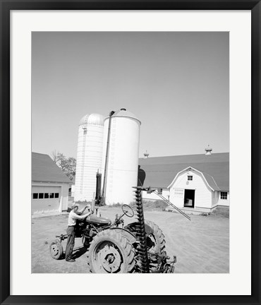 Framed USA, Farmer Working on Tractor, Agricultural Buildings in the Background Print