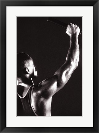 Framed Male runner holding up a relay baton Print