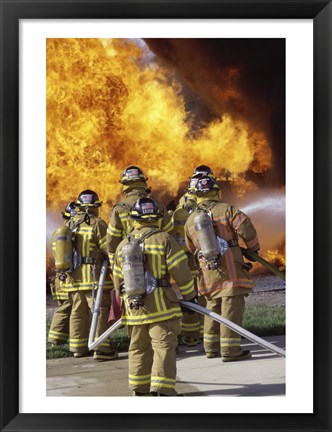 Framed Rear view of a group of firefighters extinguishing a fire vertical Print