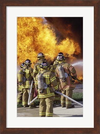 Framed Rear view of a group of firefighters extinguishing a fire vertical Print