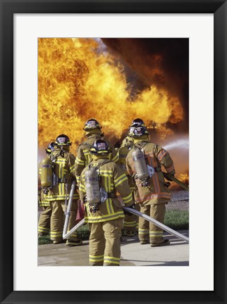 Framed Rear view of a group of firefighters extinguishing a fire vertical Print