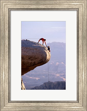 Framed Side profile of a young man pulling a young woman onto a rock Print