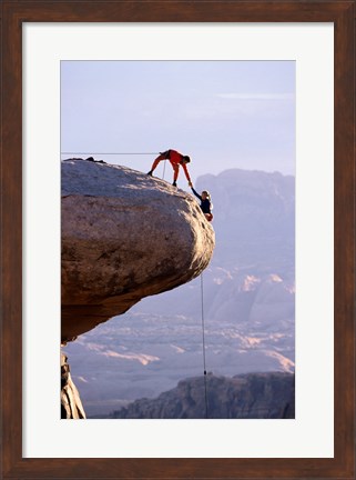 Framed Side profile of a young man pulling a young woman onto a rock Print