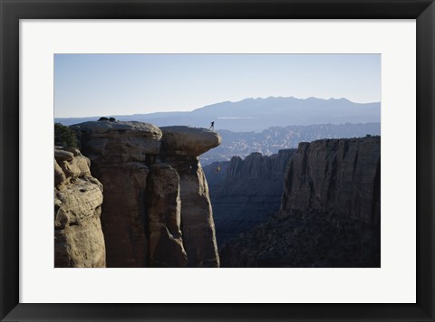 Framed Side profile of a young man pulling a young woman onto a rock Print