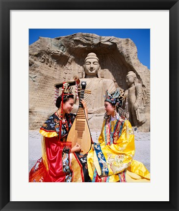 Framed Two girls in traditional costumes in front of the Buddha Statue, China Print