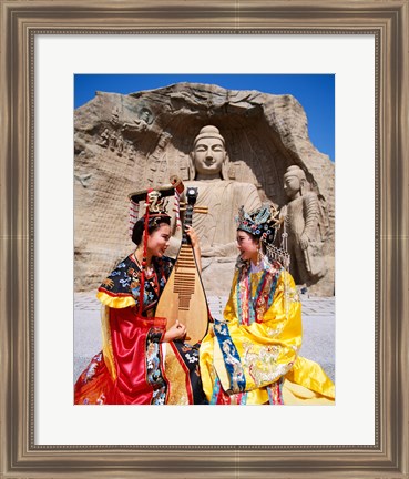 Framed Two girls in traditional costumes in front of the Buddha Statue, China Print