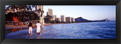 Framed Rear view of a couple wading on the beach, Waikiki Beach, Honolulu, Oahu, Hawaii, USA Print