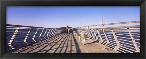 Framed Couple walking on a pier, Bay Bridge, San Francisco, California, USA Print