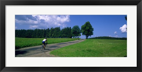 Framed Rear view of a person riding a bicycle on the road, Black Forest, Germany Print