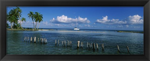 Framed Wooden posts in the sea with a boat in background, Laughing Bird Caye, Victoria Channel, Belize Print