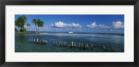 Framed Wooden posts in the sea with a boat in background, Laughing Bird Caye, Victoria Channel, Belize Print