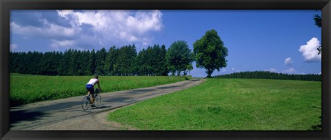 Framed Rear view of a person riding a bicycle on the road, Black Forest, Germany Print