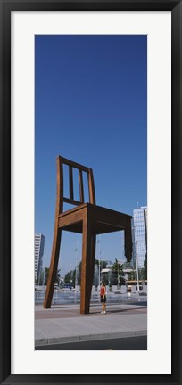 Framed Woman standing under a sculpture of large broken chair, Geneva, Switzerland Print