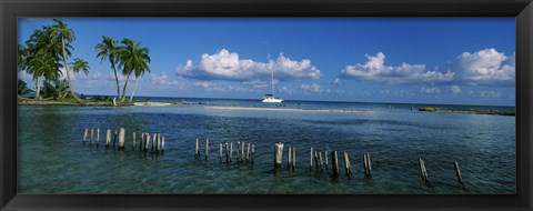 Framed Wooden posts in the sea with a boat in background, Laughing Bird Caye, Victoria Channel, Belize Print