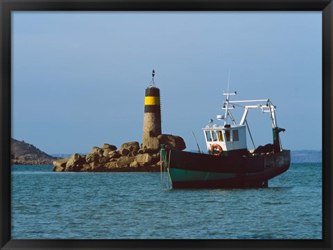 Framed Fishing trawler in front of a lighthouse at Port Saint-Sauveur, Ile Grande, Cotes-d&#39;Armor, Brittany, France Print